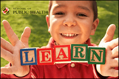 Child holding up a line of wooden letter blocks arranged to read "Learn"